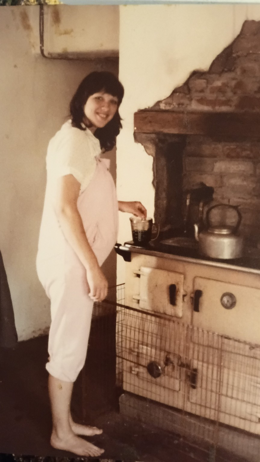 Family photograph of Branwen Buckler, pregnant, standing at the kitchen range inside Great House Farm.