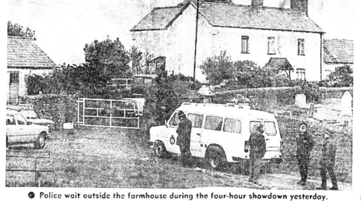 Police wait outside the farmhouse during the four-hour showdown yesterday